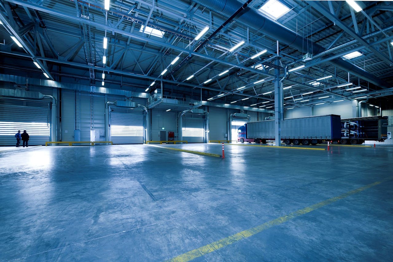 Large freight and logistics warehouse with loading bays and a trailer truck.